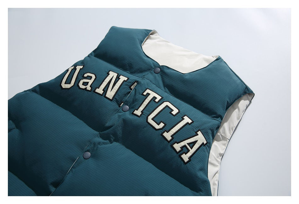 Close-up of the dark teal vest with cream varsity-style lettering, snap buttons, and cream lining.