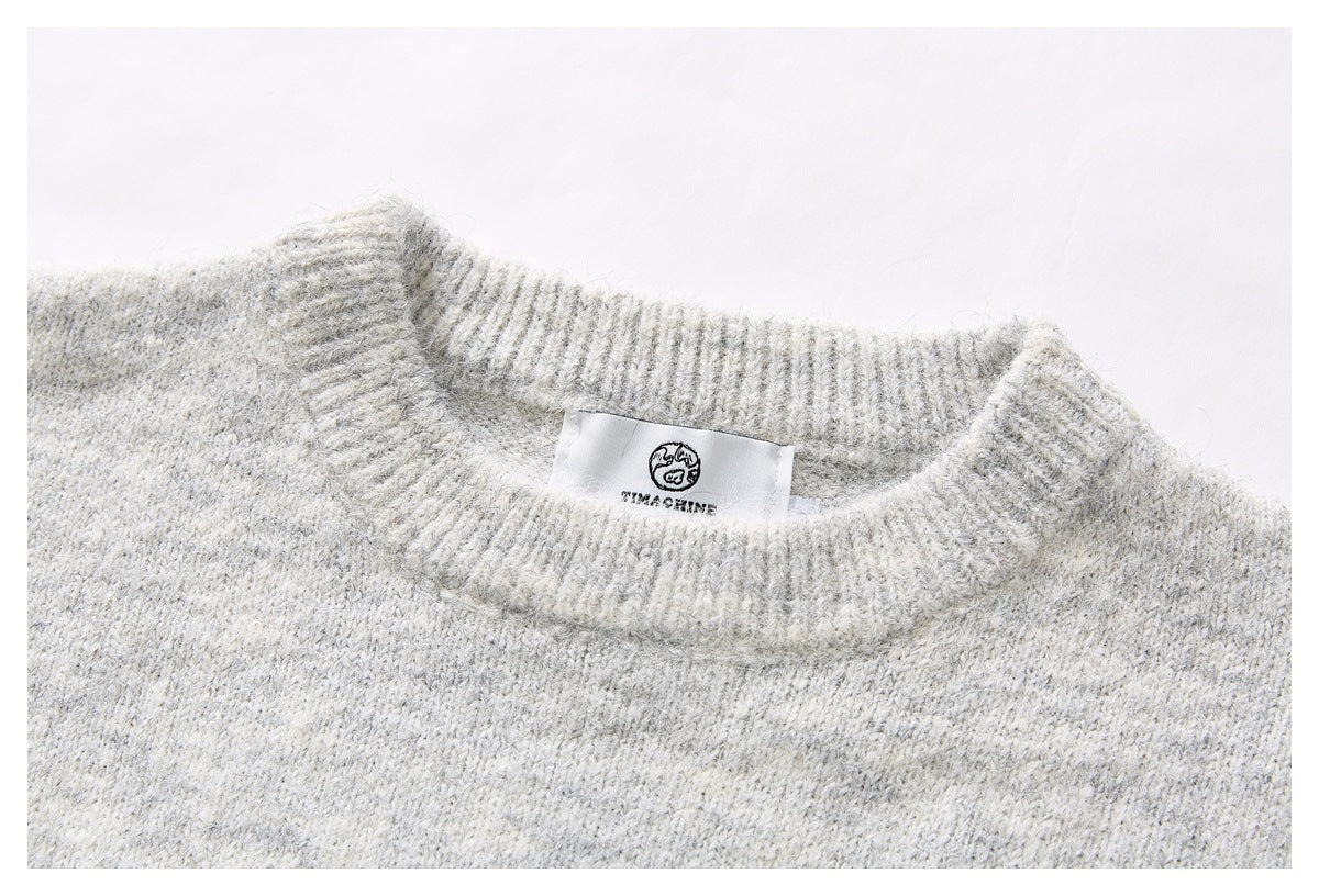 Close-up of the light gray marled sweater's ribbed crew neckline and sewn-in brand label.