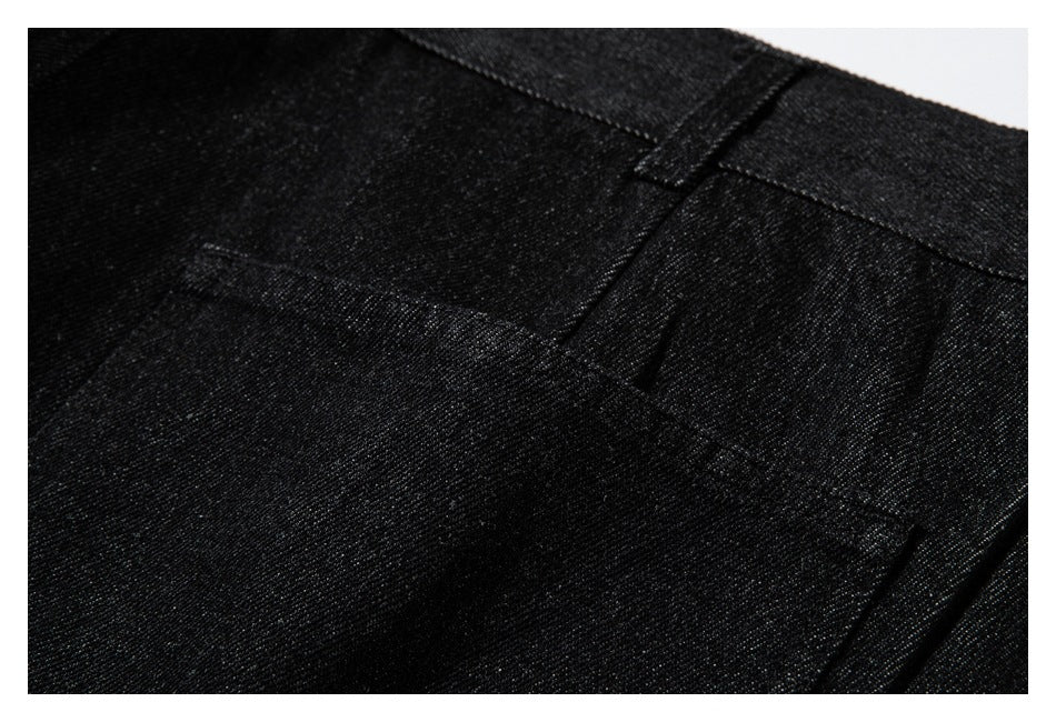 Close-up of black trousers showing the waistband, a belt loop, and a stitched pocket opening.