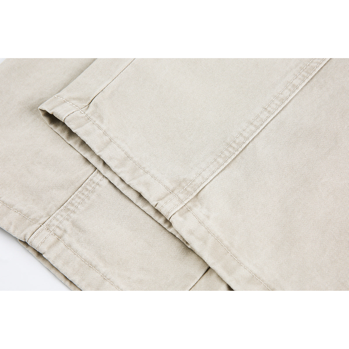 Close-up of light beige trouser fabric and a stitched folded hem.