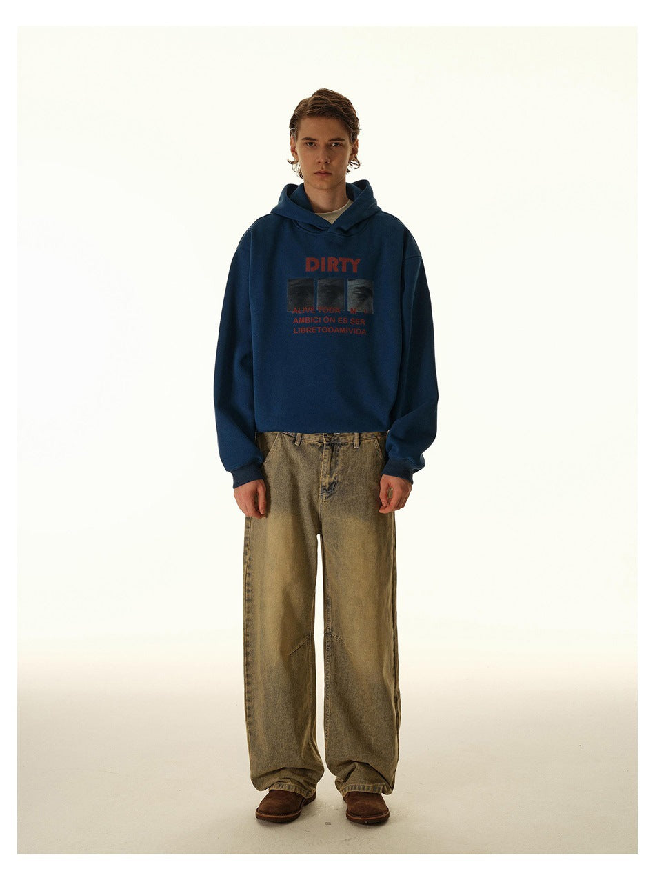 Front view of a model in a navy graphic hoodie and loose tan jeans against a light studio backdrop.