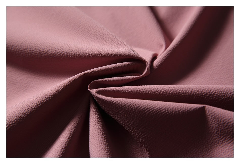 Close-up of dusty rose textured fabric folded to show its surface and drape.