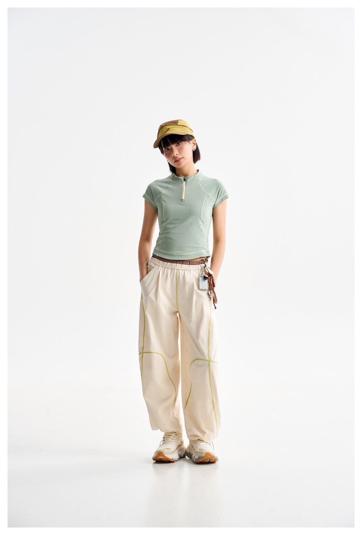 Full-length model wearing a mint zip-neck top and cream wide-leg pants with lime seam details.