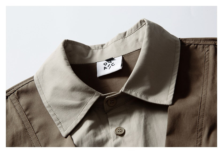 Close-up of a taupe pointed shirt collar under a brown vest, with buttons and a small neck label.