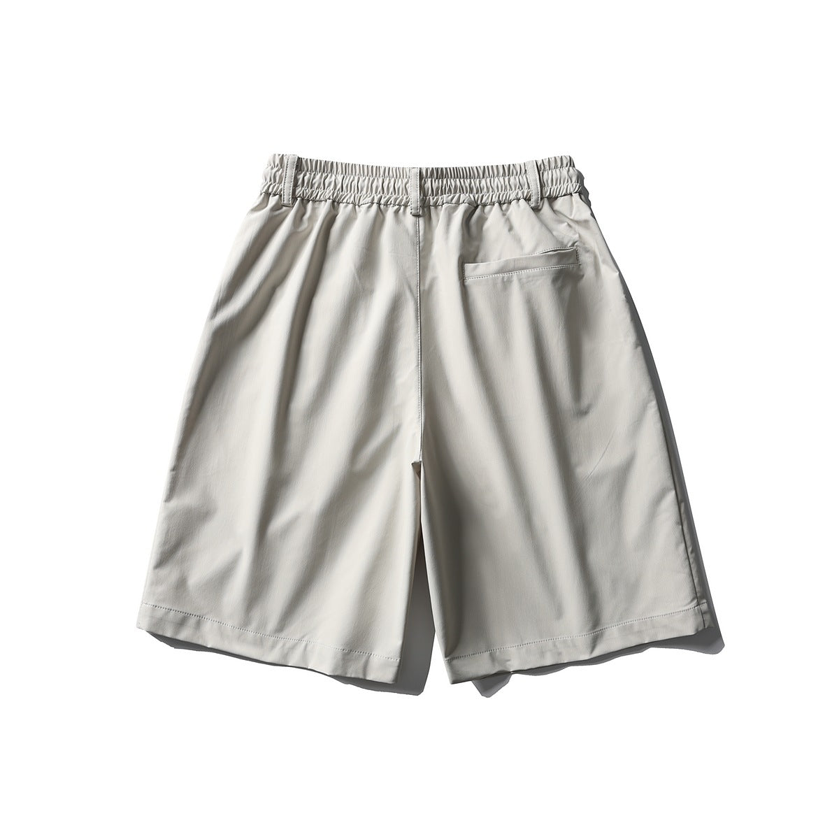 Back view of off-white shorts with elastic waistband and a single welt back pocket, flat lay
