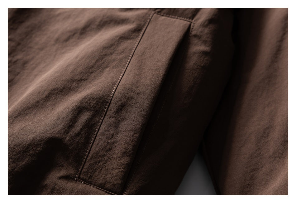 Close-up of a long vertical pocket opening on brown jacket fabric.
