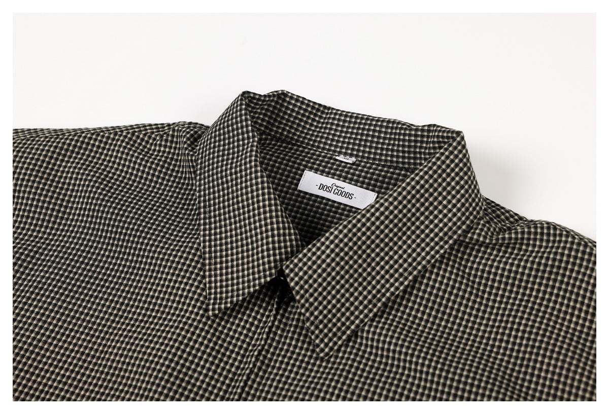 Close-up of the pointed collar and neck label on a black and beige micro-check shirt.
