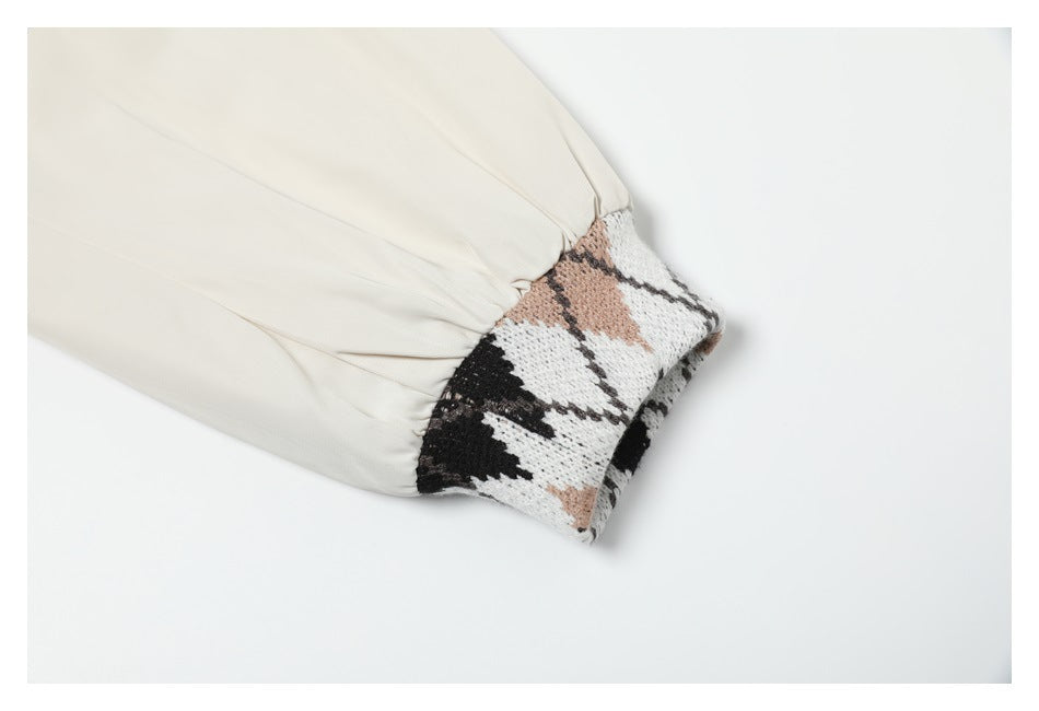 Close-up of an ivory jacket sleeve with an elasticated seam and a black, white, and tan patterned knit cuff.