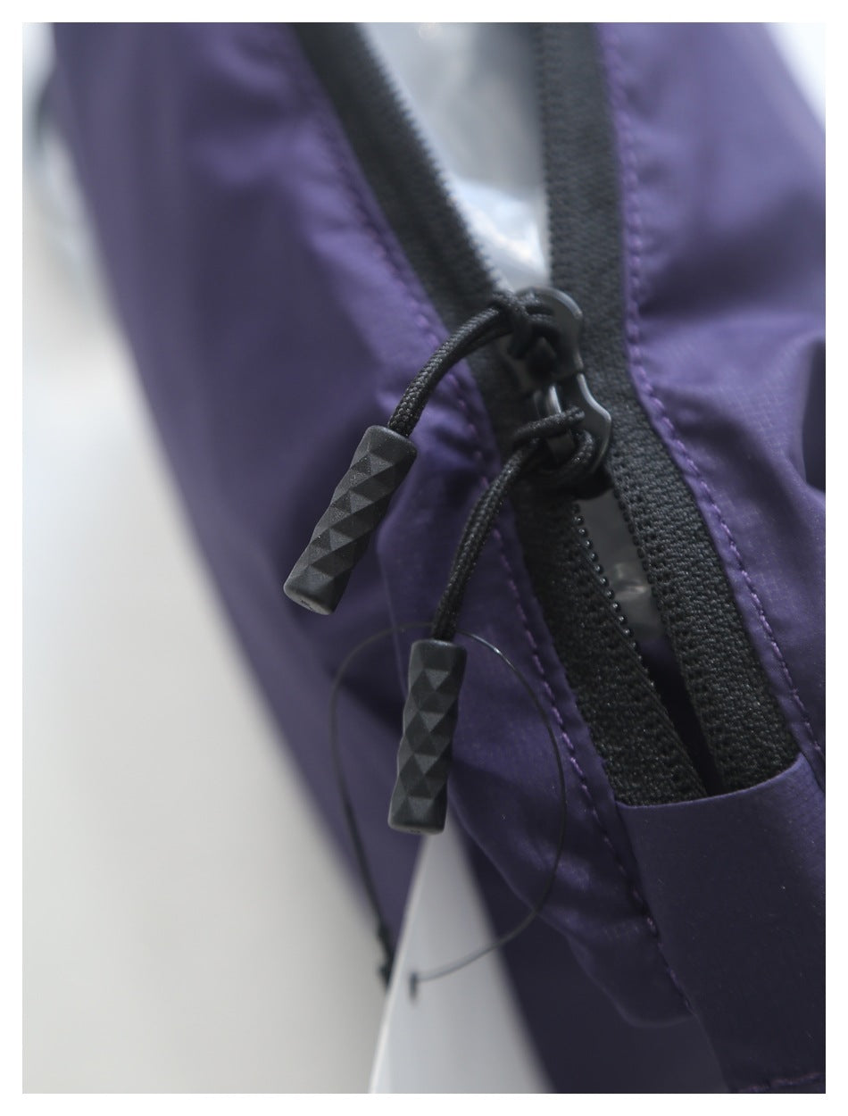 Close-up of a purple garment with a black zipper and two textured black cord pulls.
