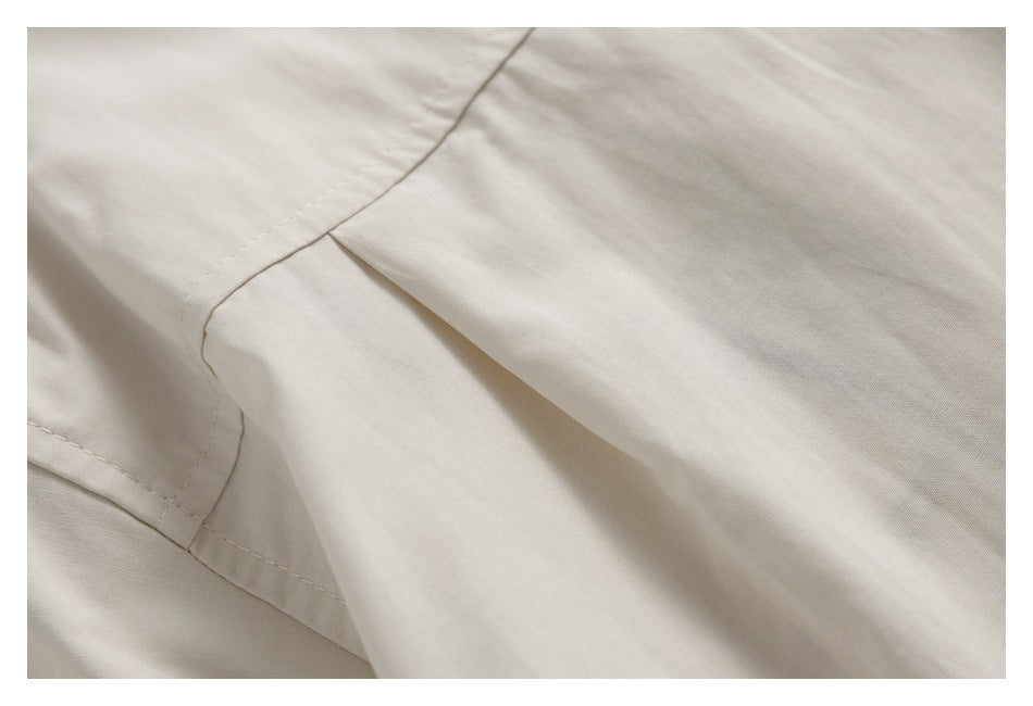 Close-up of a stitched seam and overlapping folds in pale beige fabric.