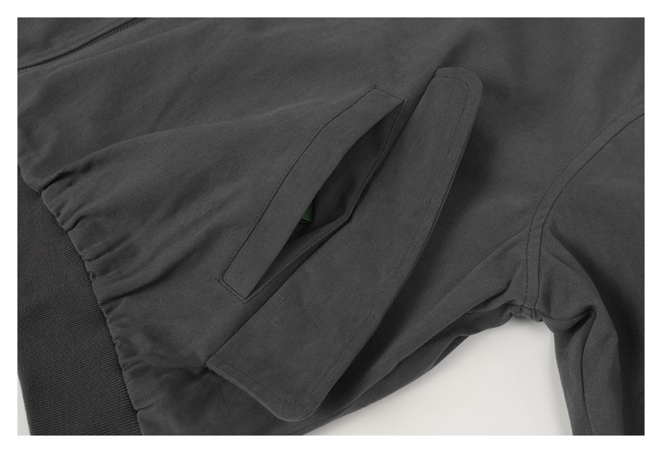 Close-up of the charcoal jacket's sleeve flap pocket, stitching, and ribbed hem.