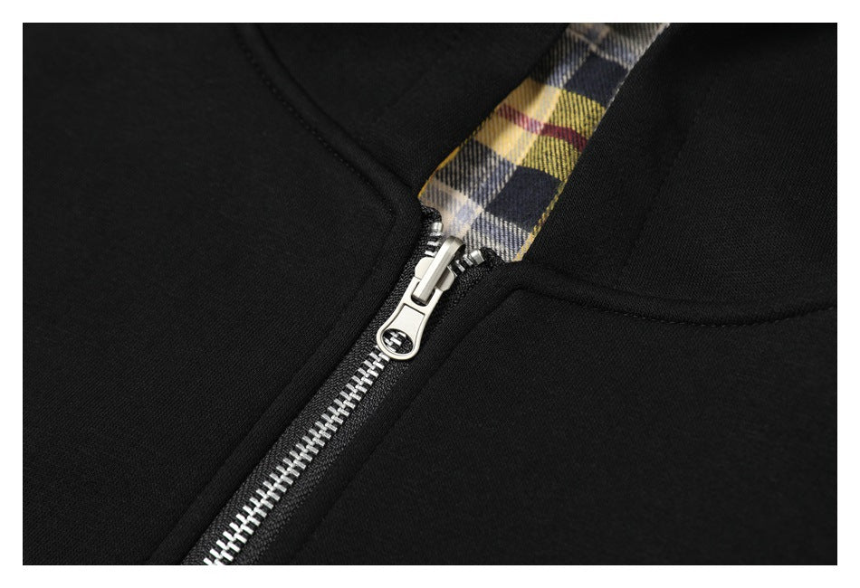 Close-up of the silver zipper and plaid-lined opening on a black hoodie.
