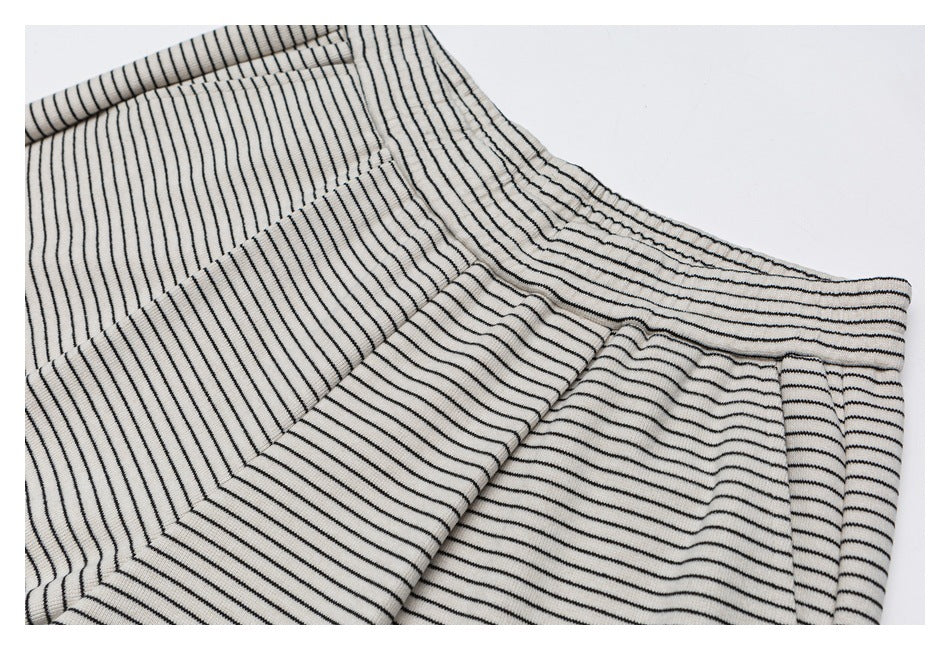 Close-up of cream pants with narrow black stripes, showing the elastic waistband and pocket construction.