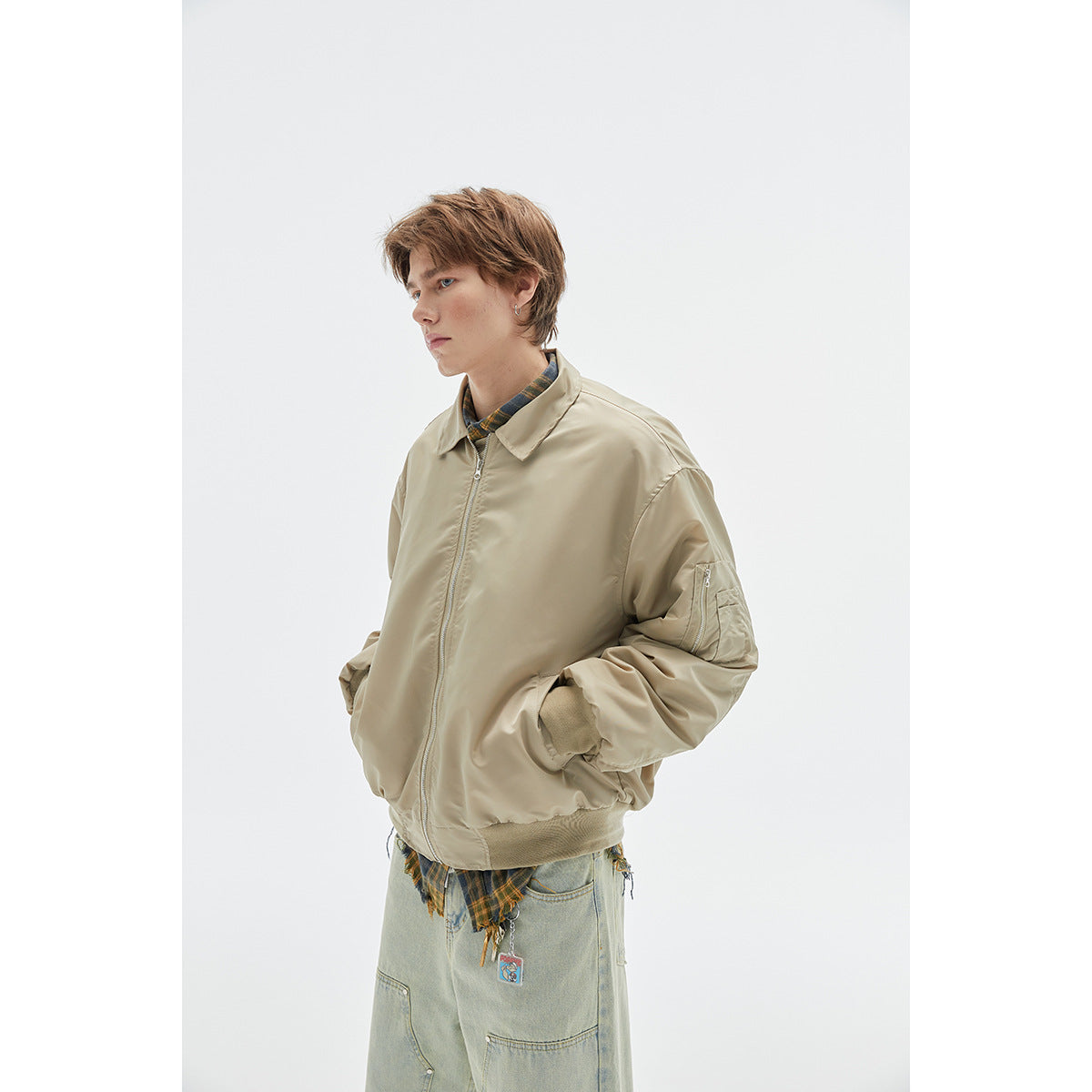 Closer view of a model wearing a light beige zip-front jacket with a collar, ribbed cuffs, and sleeve pocket.