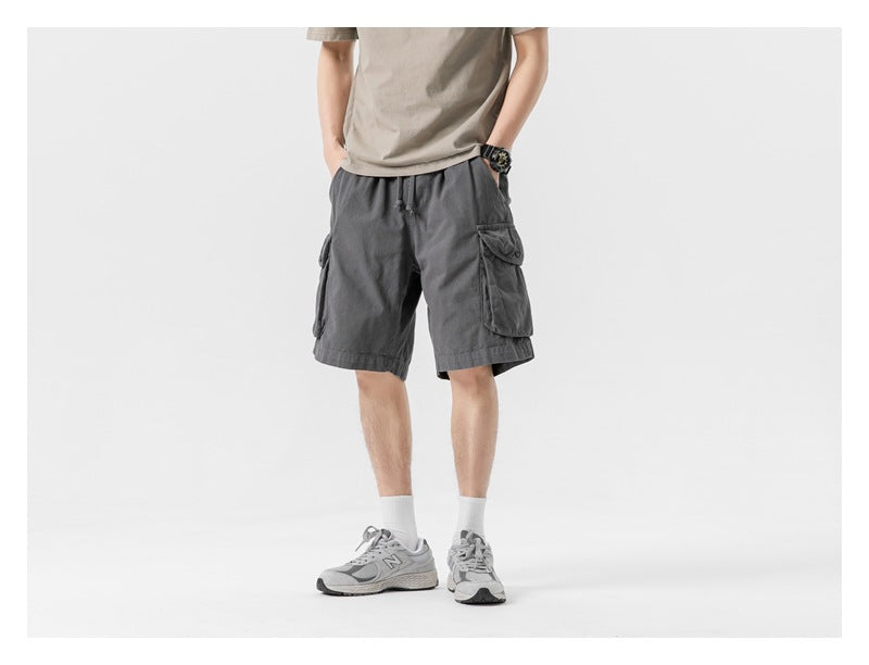 Model wearing charcoal gray cargo shorts, shown from the front with hands in pockets.