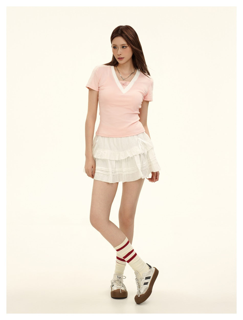 Model wearing the pink V-neck short-sleeve top with a white tiered mini skirt, striped socks and sneakers