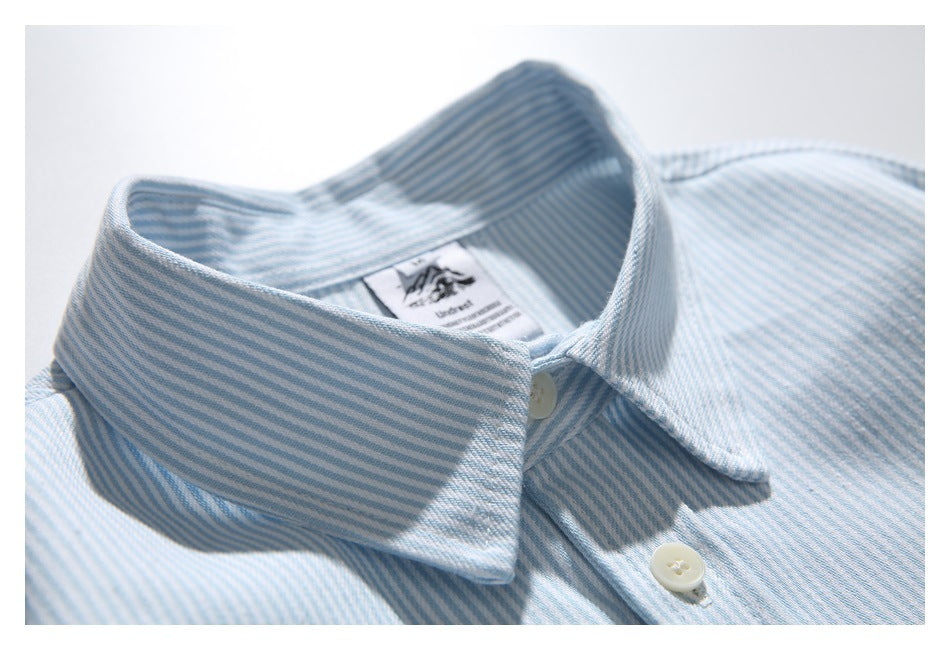 Close-up of the striped shirt's pointed collar, top button, and inner neck label.