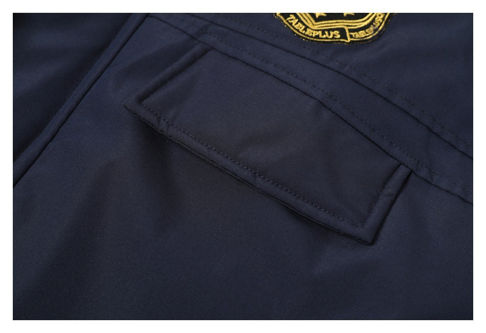 Close-up of a dark navy garment pocket with a partially visible gold embroidered patch.