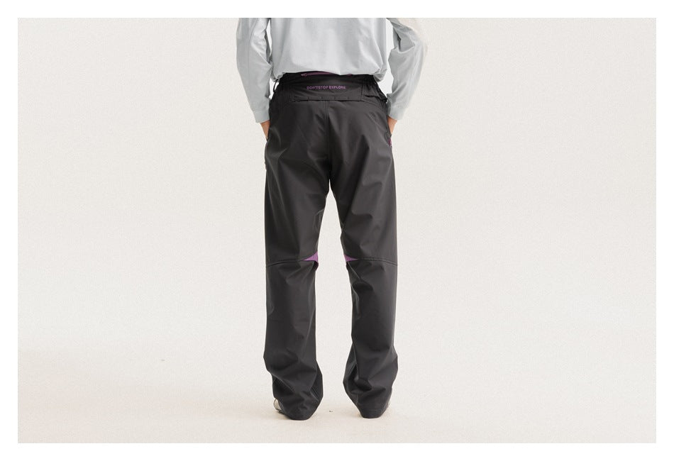 Rear view of a model wearing black trousers with purple accents at the knees and waistband.