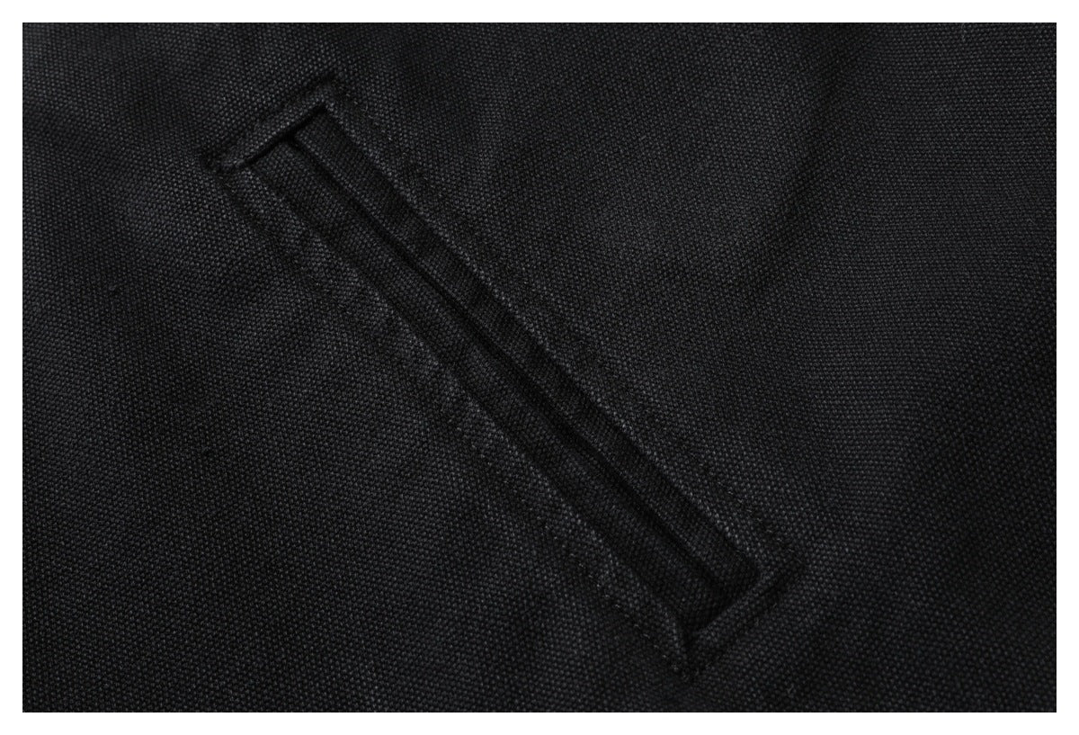 Close-up of a narrow diagonal welt pocket on black textured jacket fabric.