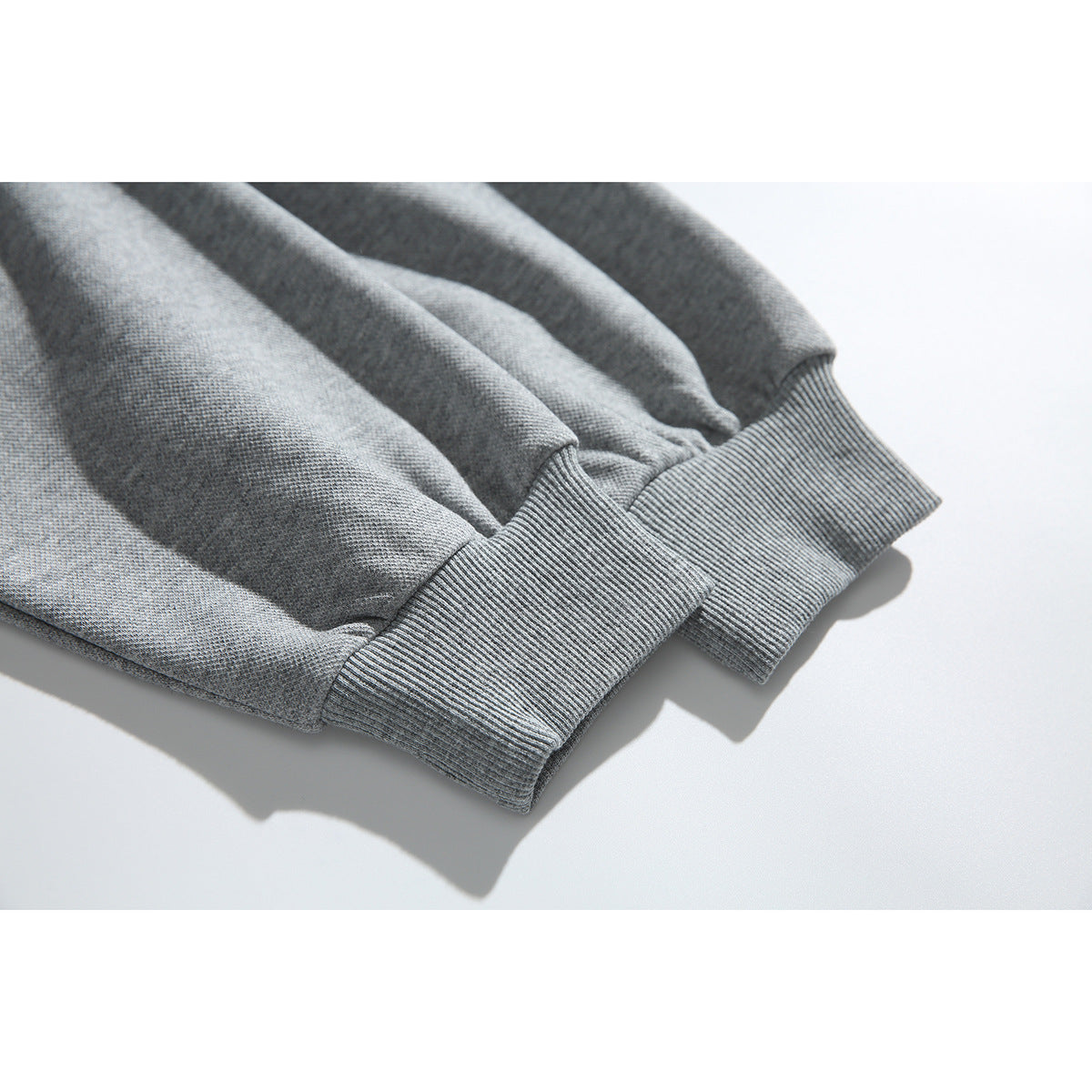 Close-up of the ribbed cuffs on the sleeves of a heather gray pullover.