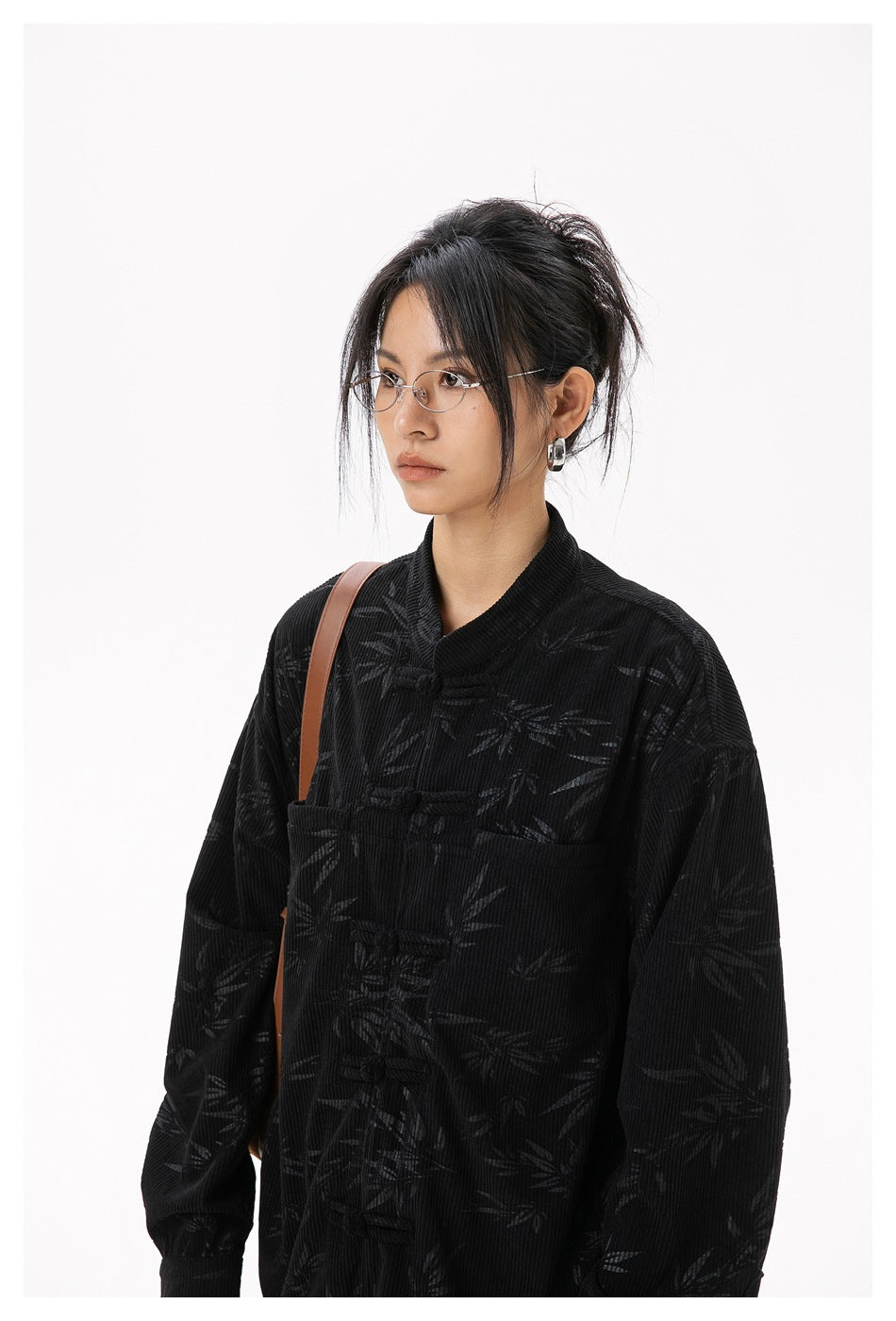 Model wearing a black bamboo-patterned jacket with a stand collar and frog closures.
