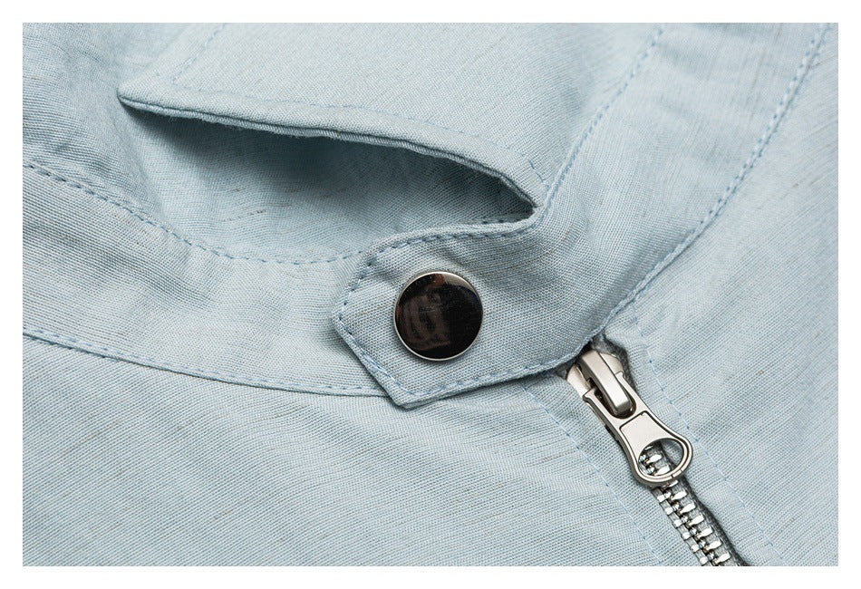 Close-up of a metal zipper and dark button fastening on a pale blue garment.
