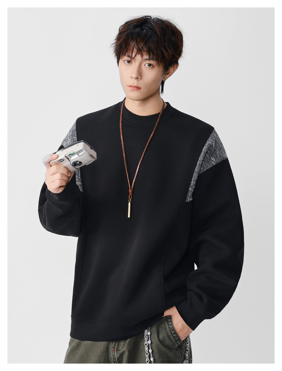 Model wearing a black crewneck sweatshirt with gray textured shoulder panels and ribbed cuffs.
