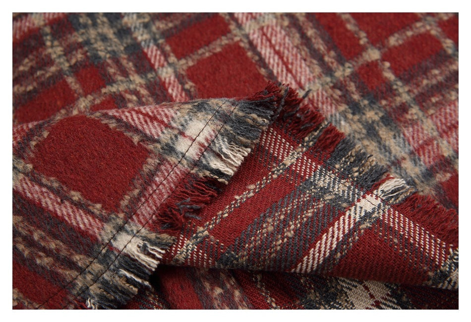 Close-up of red, charcoal, cream, and tan plaid fabric with a stitched, frayed edge.