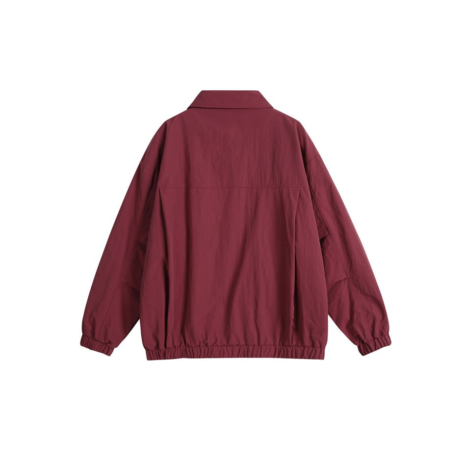 Back view of a burgundy jacket with a collar, long sleeves, elastic cuffs and gathered elastic hem.