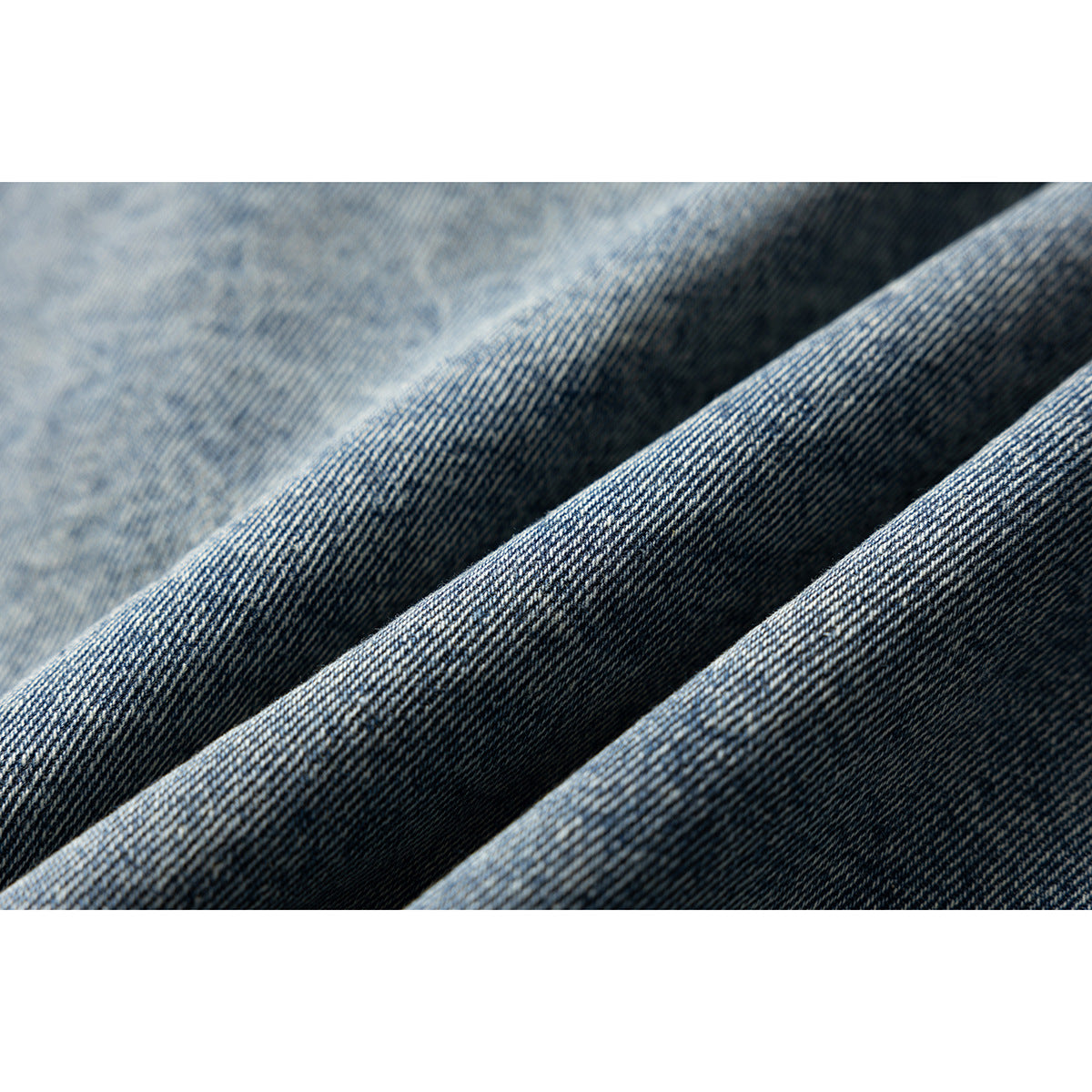 Close-up of folded blue denim showing its diagonal weave and varied wash.