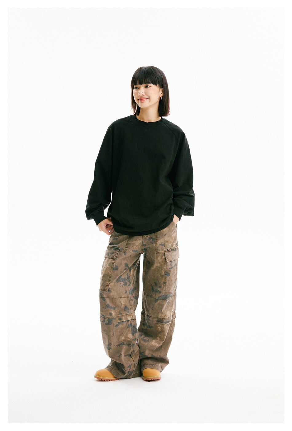 Model wearing an oversized black crewneck sweatshirt with raglan sleeves and brown camouflage cargo pants.