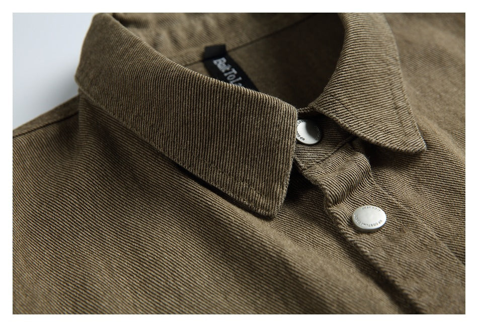 Close-up of the brown-olive jacket's pointed collar, inner neck label, and silver snap buttons.