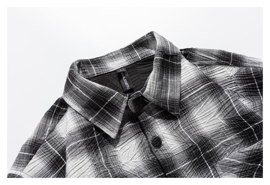 Close-up of a black, gray, and white plaid shirt collar, neckline, and front button.