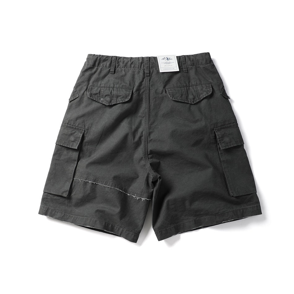 Dark charcoal gray cargo shorts flat lay, back view, with flap back pockets, side cargo pockets and frayed hem