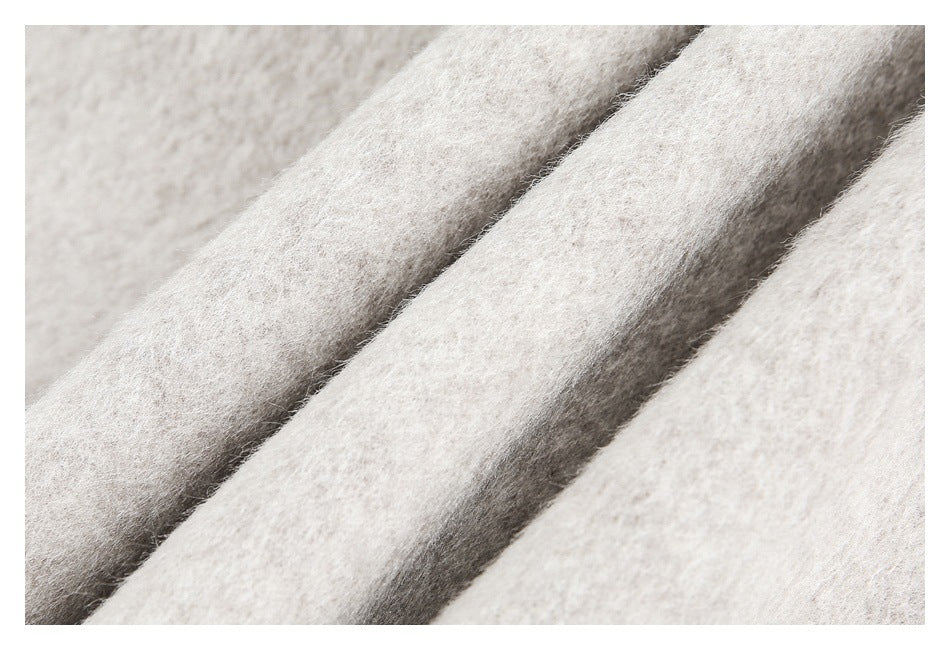 Macro view of the pale beige coat's fuzzy fabric folded into soft ridges.