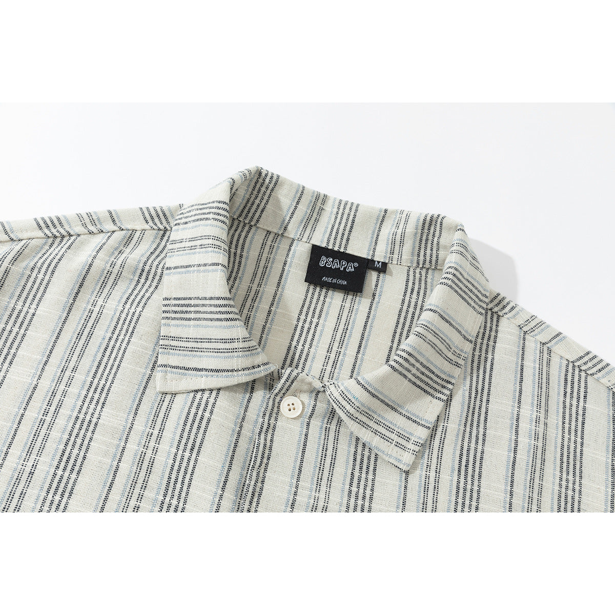 Close-up of an ivory striped button-up shirt collar, showing the top button and neck label.