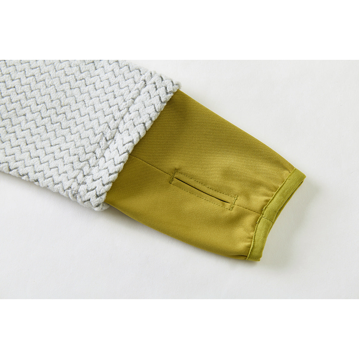 Close-up of the patterned sleeve turned back to show a mustard-colored cuff with a narrow slit.