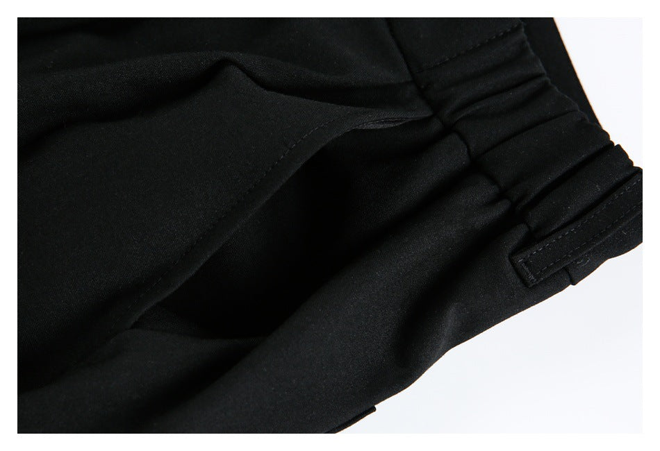 Close-up of a side pocket opening and gathered elastic section of the black shorts' waistband.