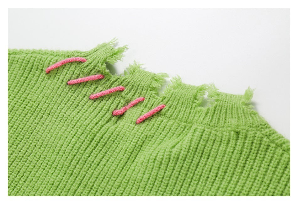 Close-up of lime-green ribbed knit with a distressed edge and several pink embroidered bars.