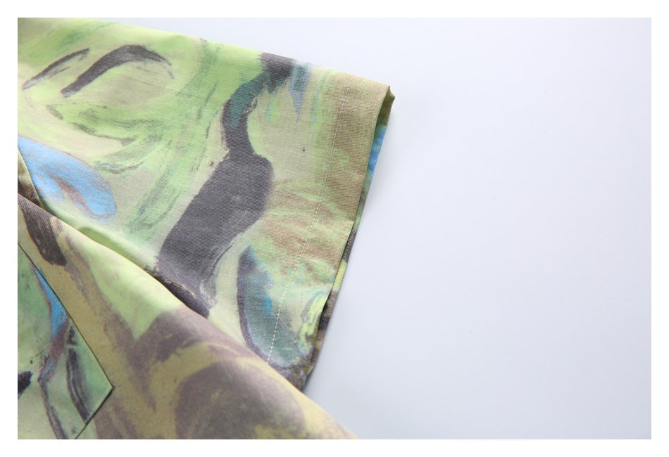 Close-up of a sleeve cuff on a shirt with a lime, blue, and charcoal abstract floral print.