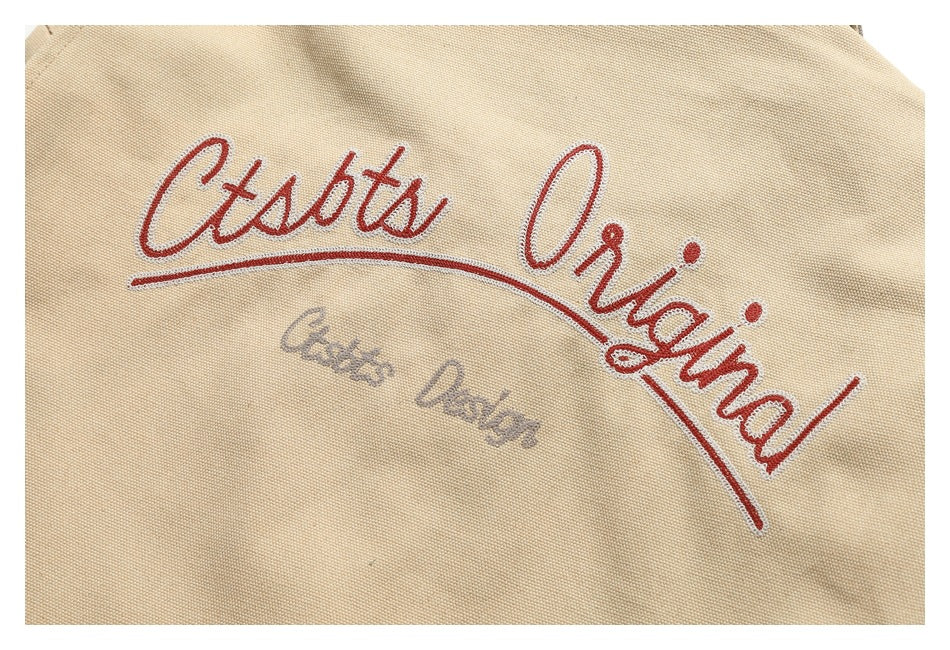 Close-up of red and gray script embroidery on a beige textured garment.