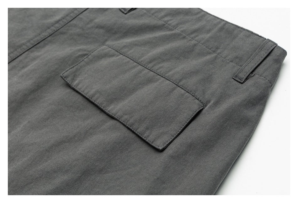 Close-up of charcoal-gray trousers showing a rectangular patch pocket and belt loop.