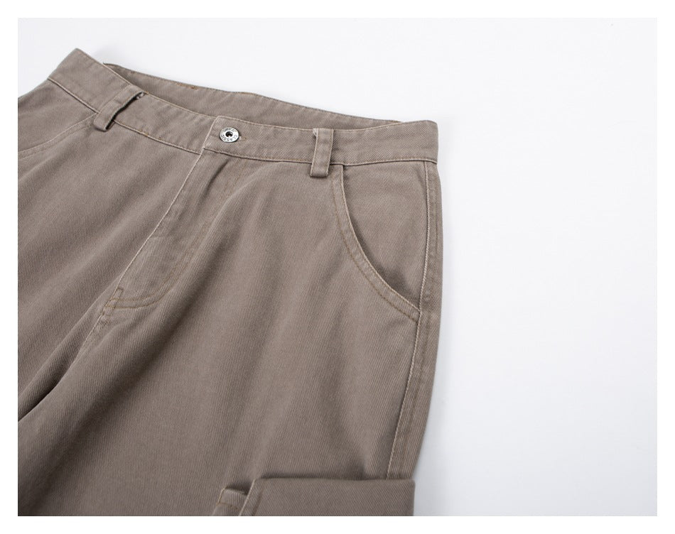 Angled close-up of taupe trousers showing the waistband, button, belt loops and side pocket.