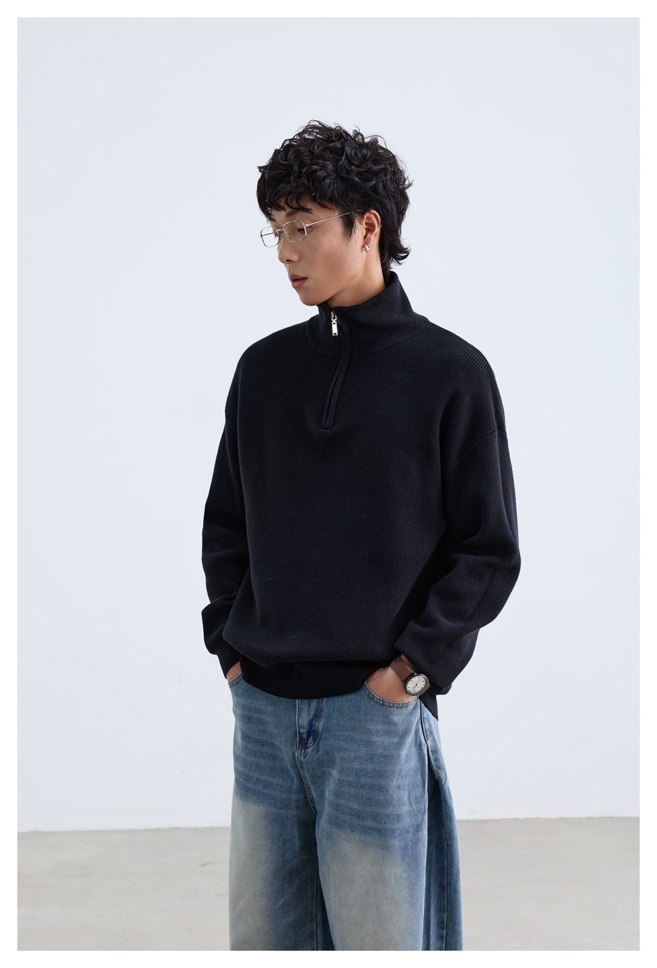 Model wearing a black ribbed quarter-zip sweater with a high collar and relaxed fit.