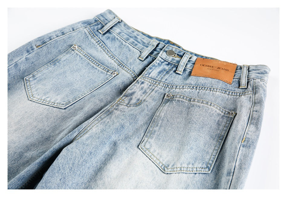 Close-up of light-wash jeans showing the rear pockets, waistband, belt loops, stitching, and leather brand patch.