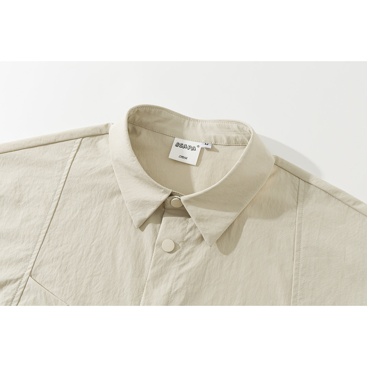 Close-up of an ivory short-sleeve shirt collar, top buttons, and neck label.