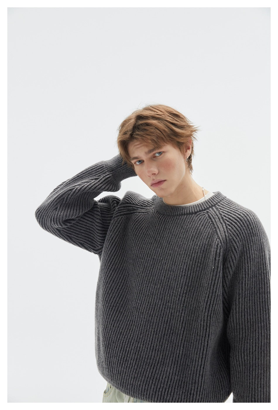 Model wearing a dark gray ribbed crewneck sweater with raglan sleeves, shown from the waist up.