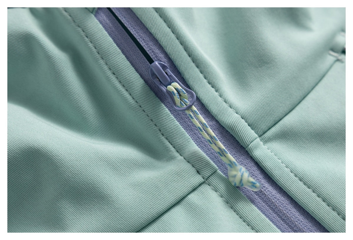 Close-up of a pale mint jacket's lavender zipper with a patterned pull cord and stitched seams.
