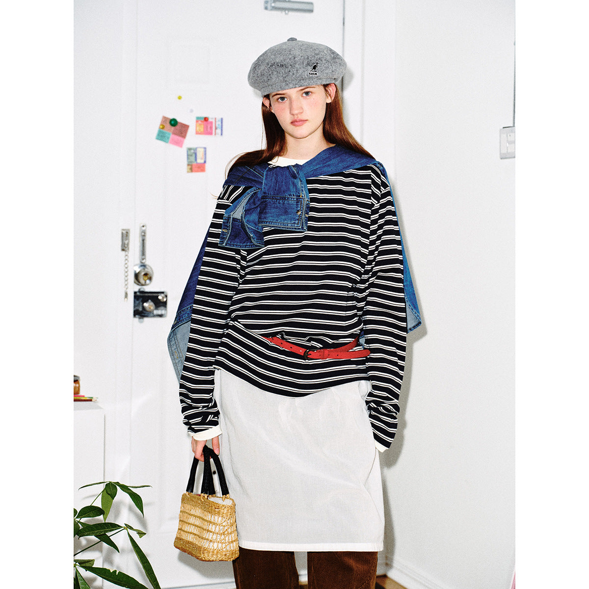 Closer view of a model wearing an oversized black top with thin white stripes, layered with a white apron-style garment and